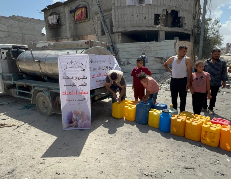 An Alalusi Foundation water tanker delivering clean water to families queuing with jerry cans amid damaged buildings in Gaza, Palestine